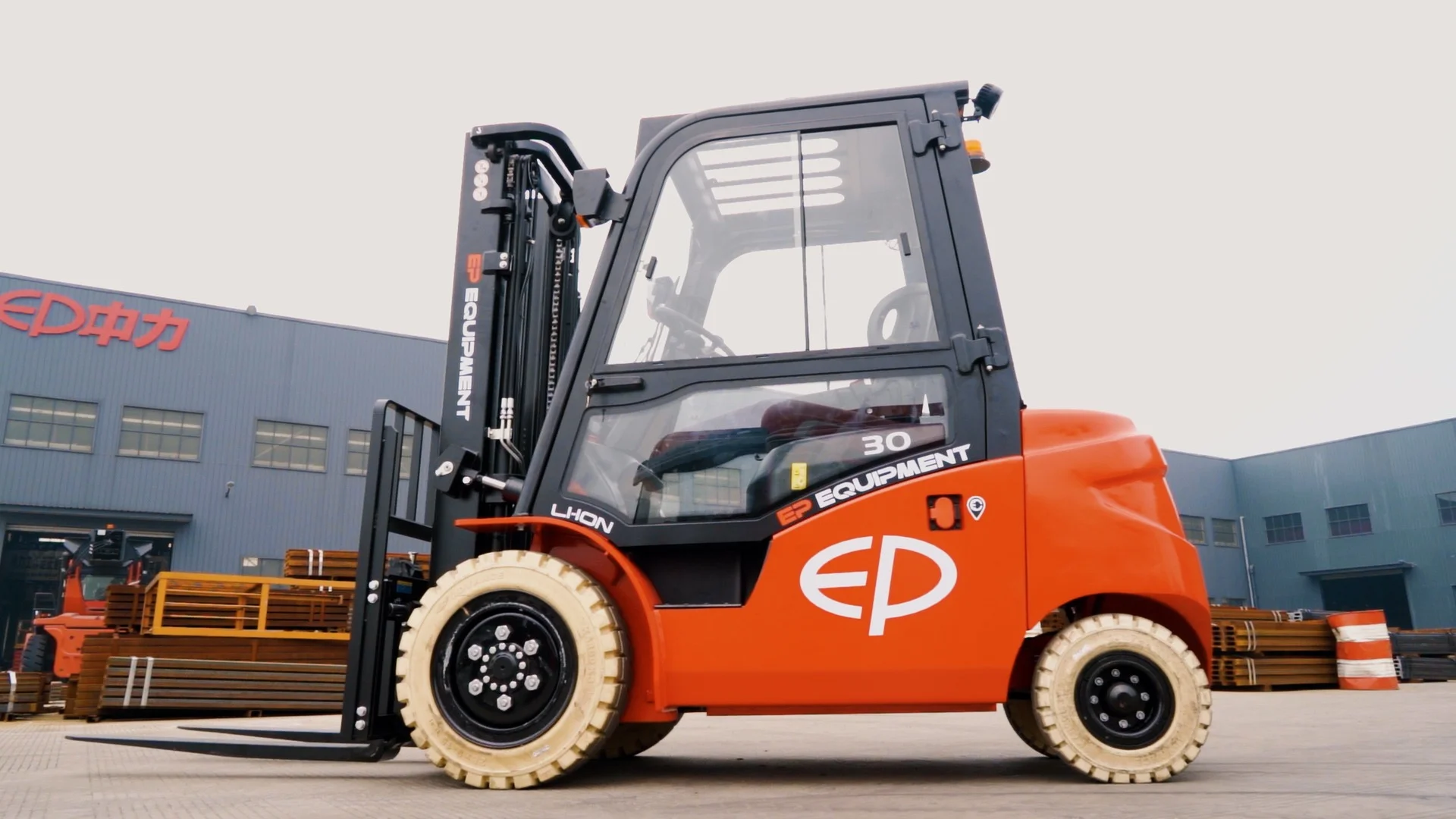 EFL303 four-wheel lithium counterbalance forklift by EP Equipment parked outside factory with full cabin enclosure
